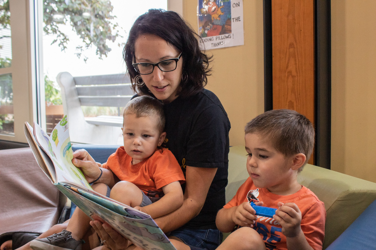 Adult reading a book to two children